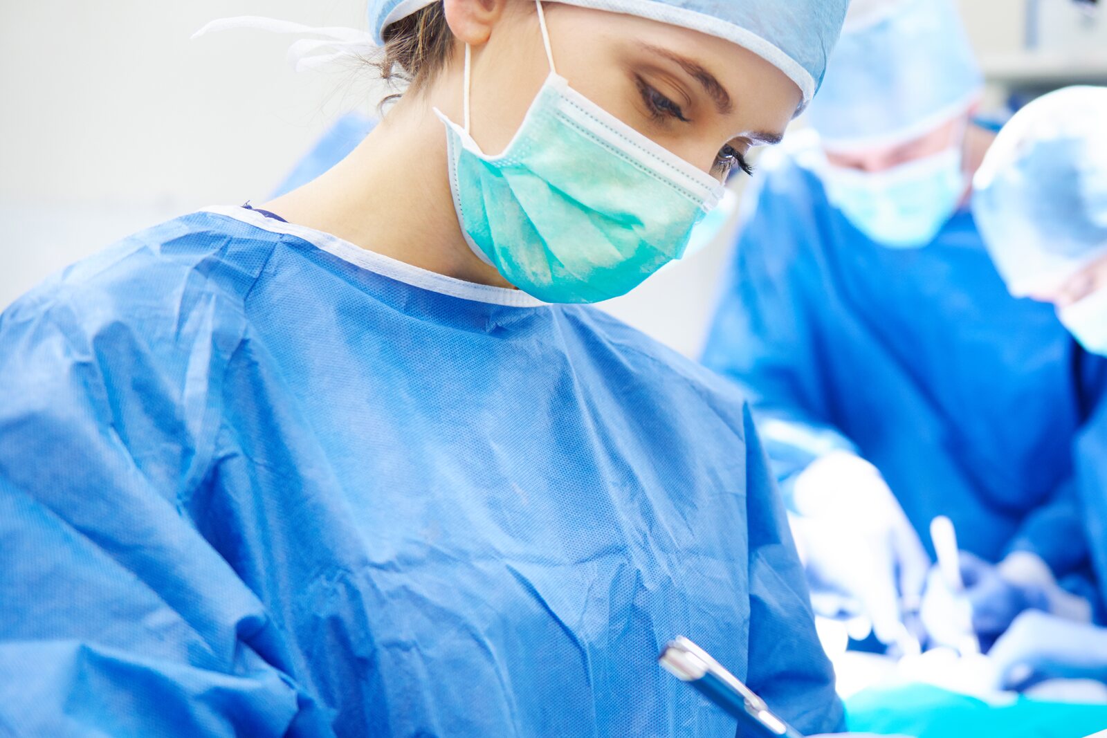 Professionista sanitaria in camice sterile e mascherina durante un'attività clinica